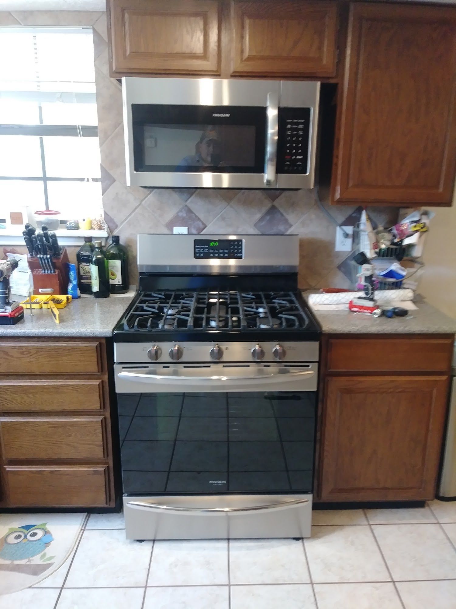 Kitchen with stainless steel oven and microwave, wooden cabinets, and tiled backsplash.