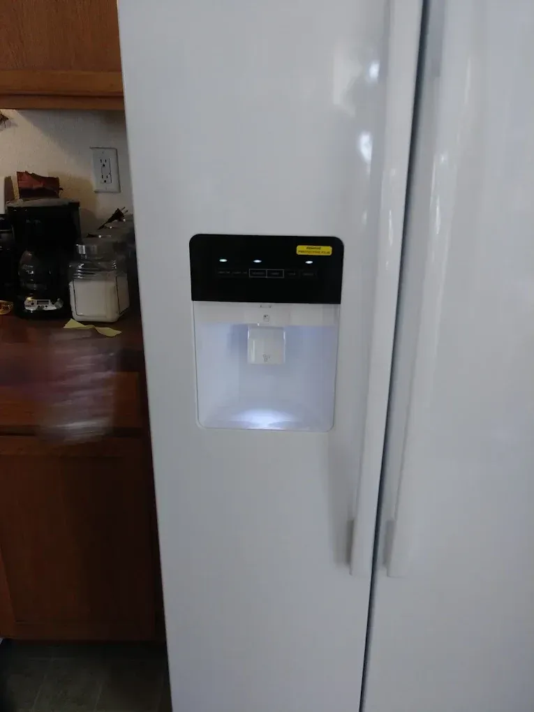 White refrigerator with water dispenser illuminated.