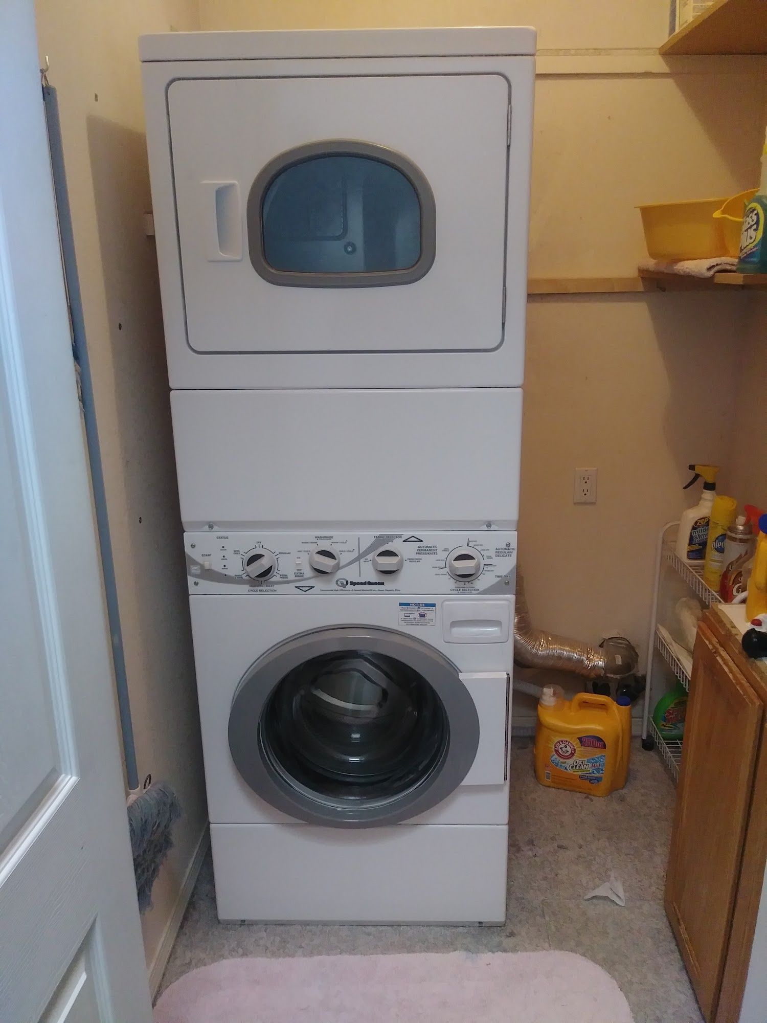 Stacked white washer and dryer in a small laundry room.