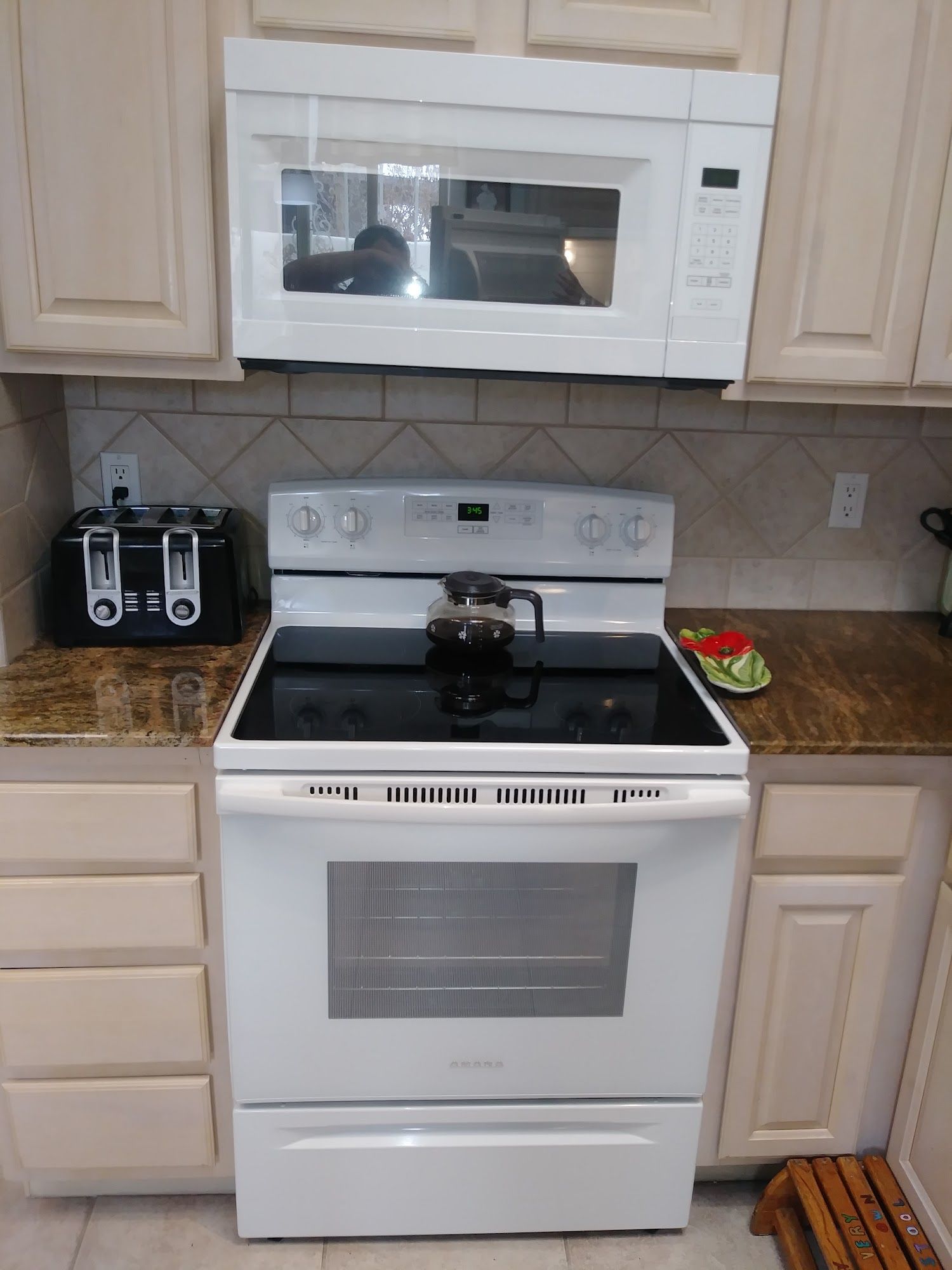 White kitchen with a stove, microwave, and toaster on a countertop.