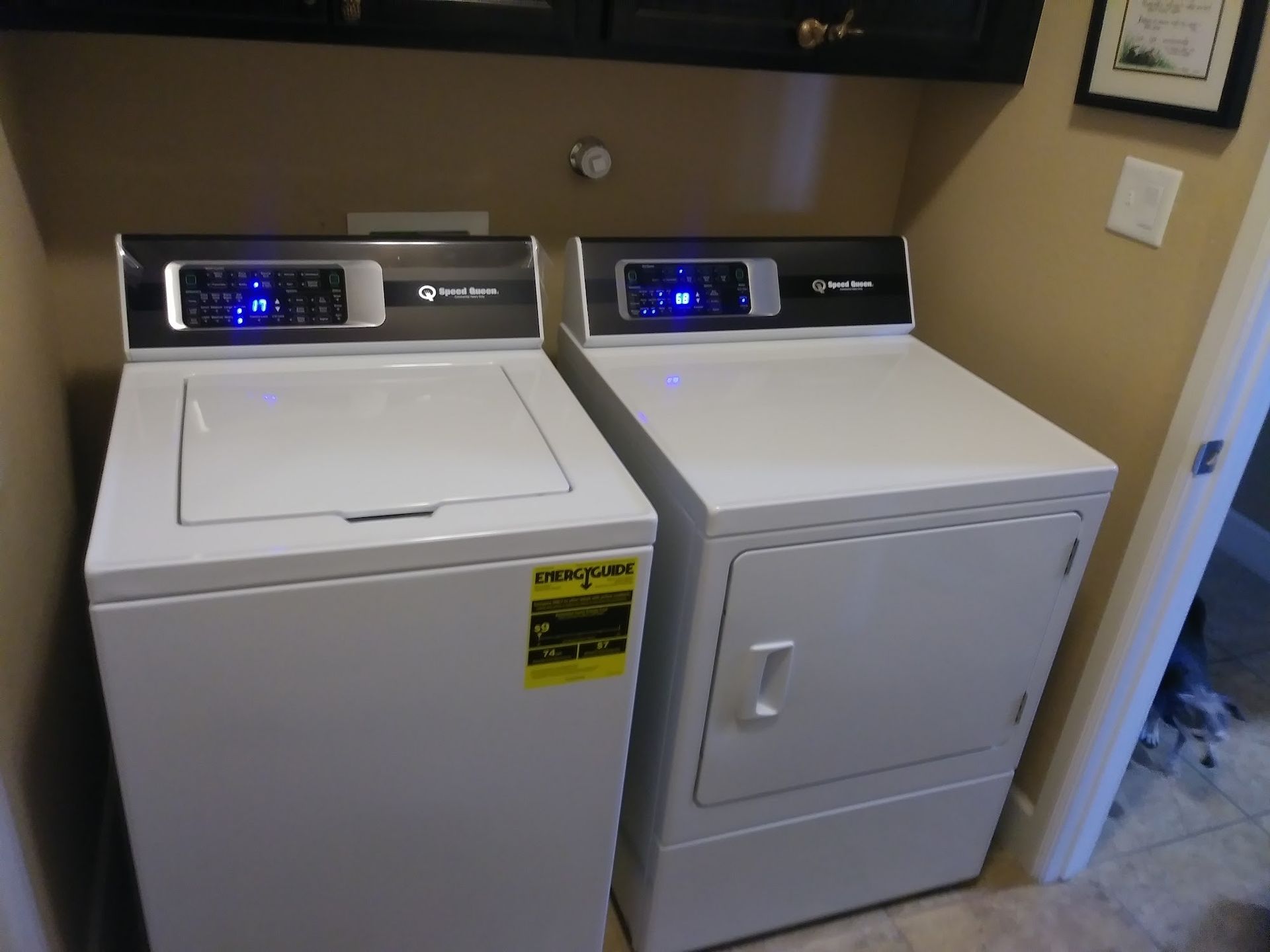 White washer and dryer appliances in a laundry room, under a cabinet.
