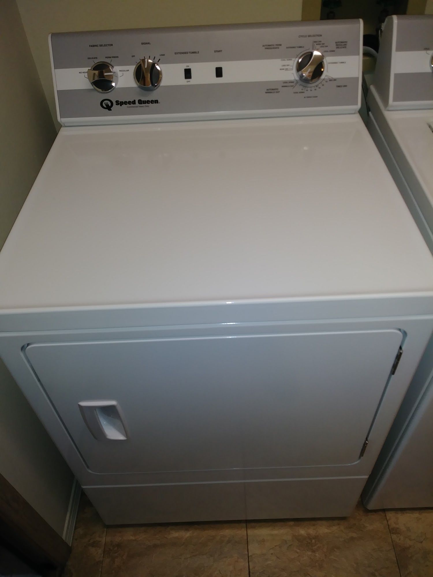White, front-loading dryer with control knobs on top panel.