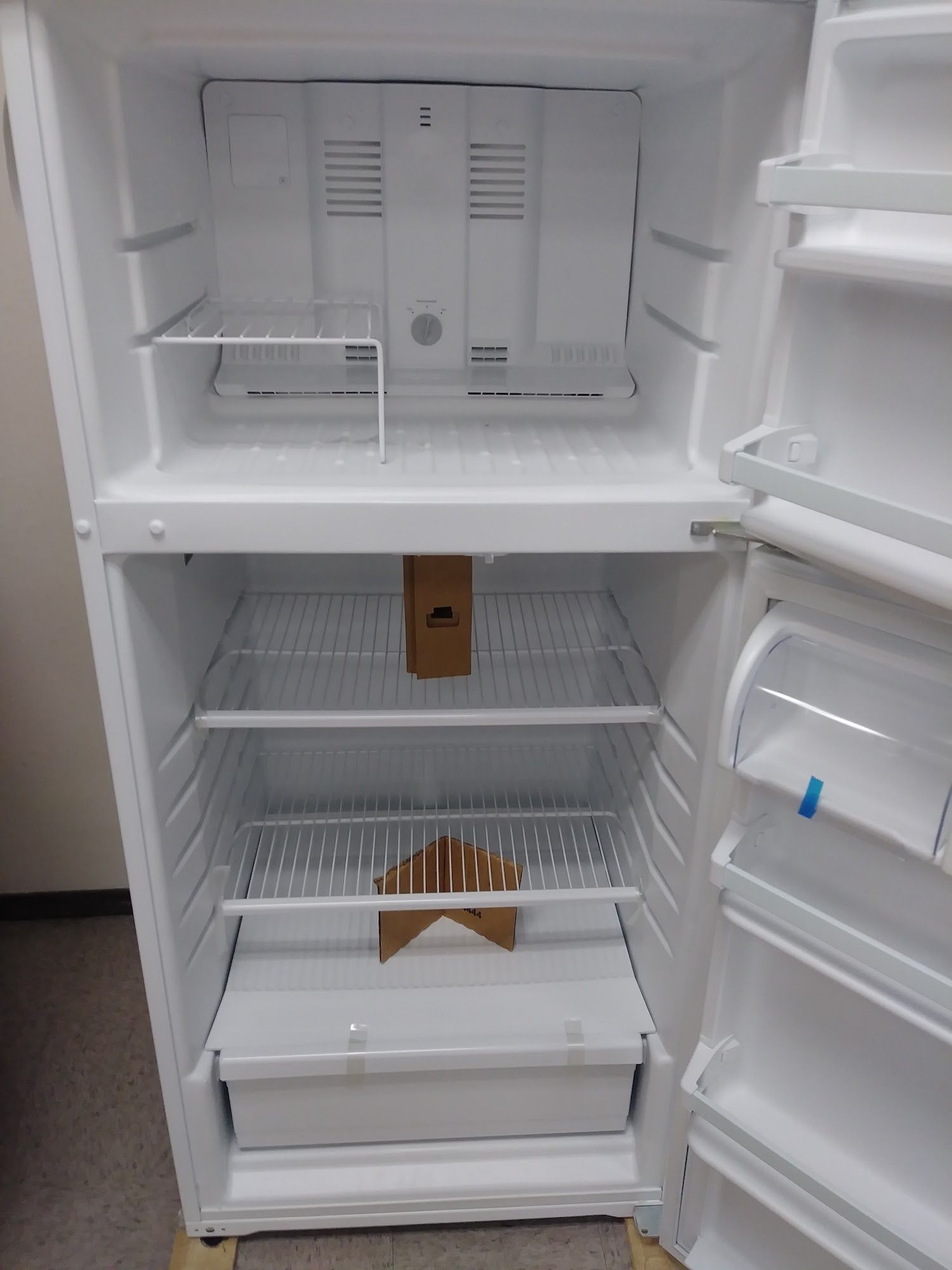 Opened empty white refrigerator interior with shelves and freezer on top.