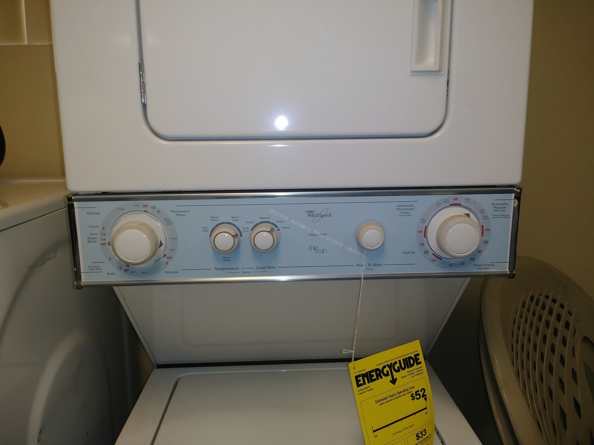 Stackable white Whirlpool washer and dryer unit with blue control panel. Energy guide tag.