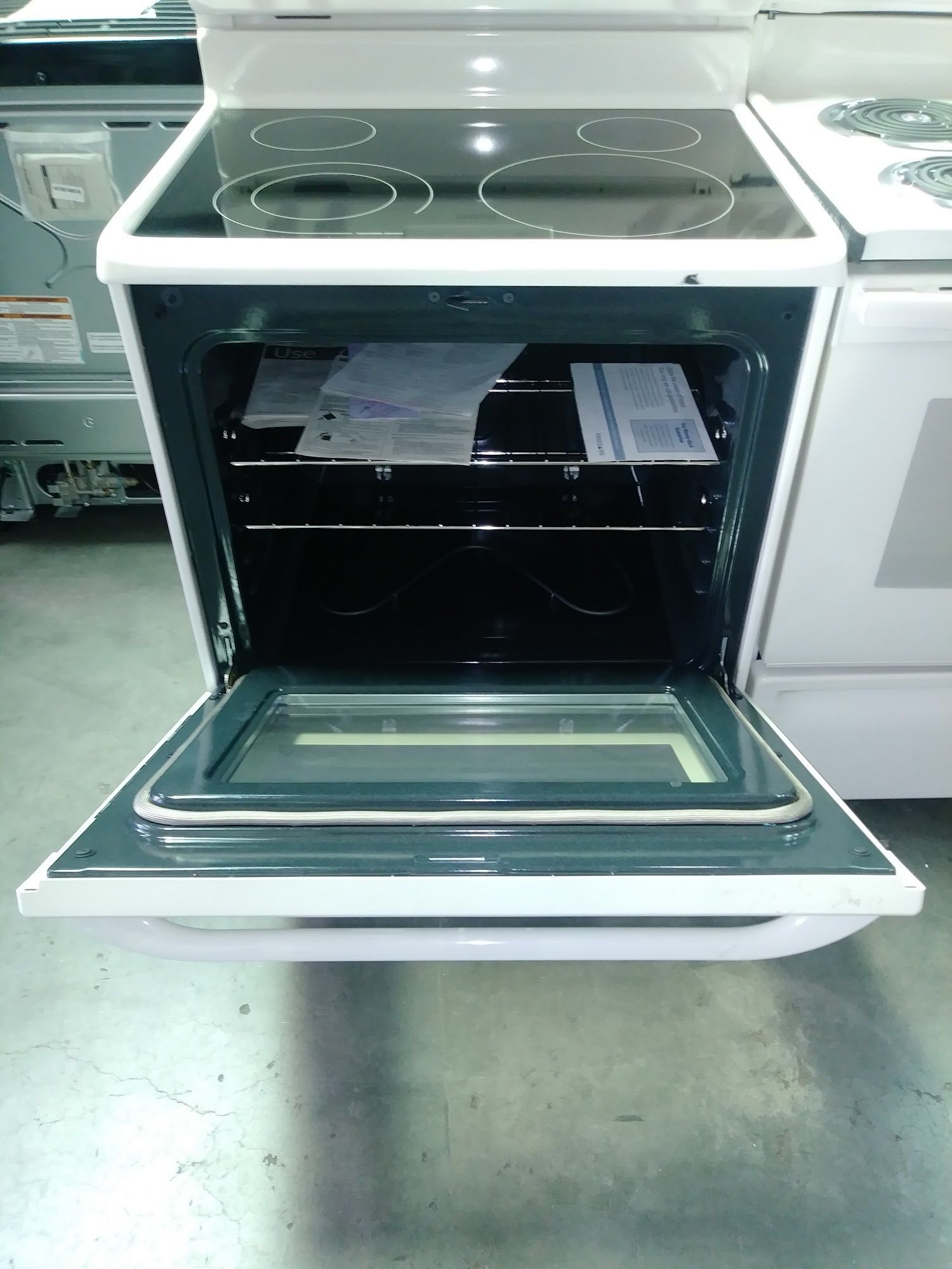 White electric oven with open door, black stovetop, and empty interior.