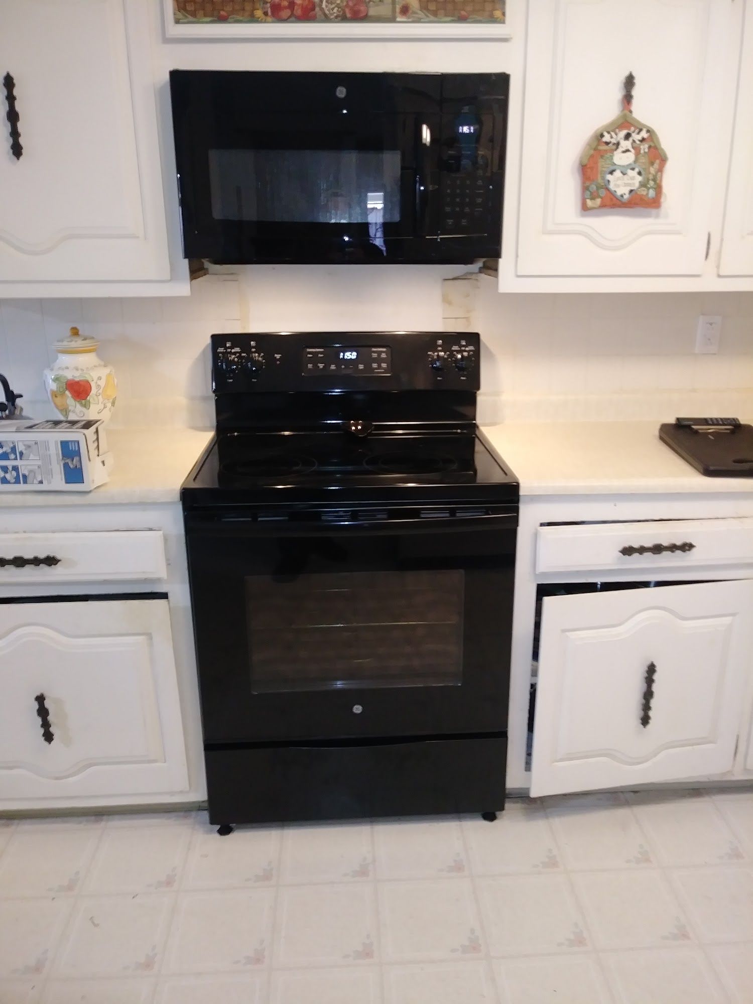 Black oven and microwave in a white kitchen.