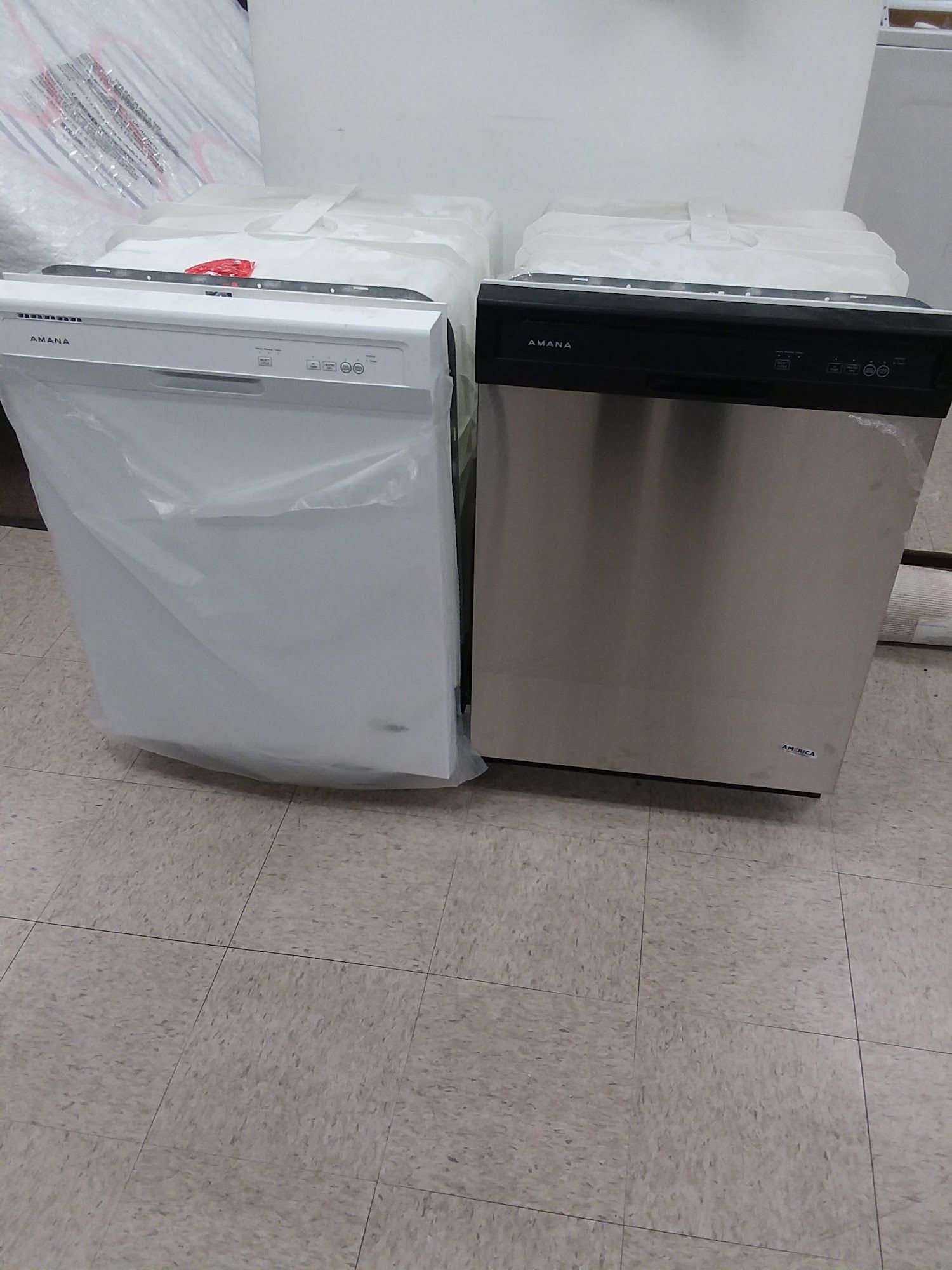 Two dishwashers, one white, one stainless steel, on a tiled floor.