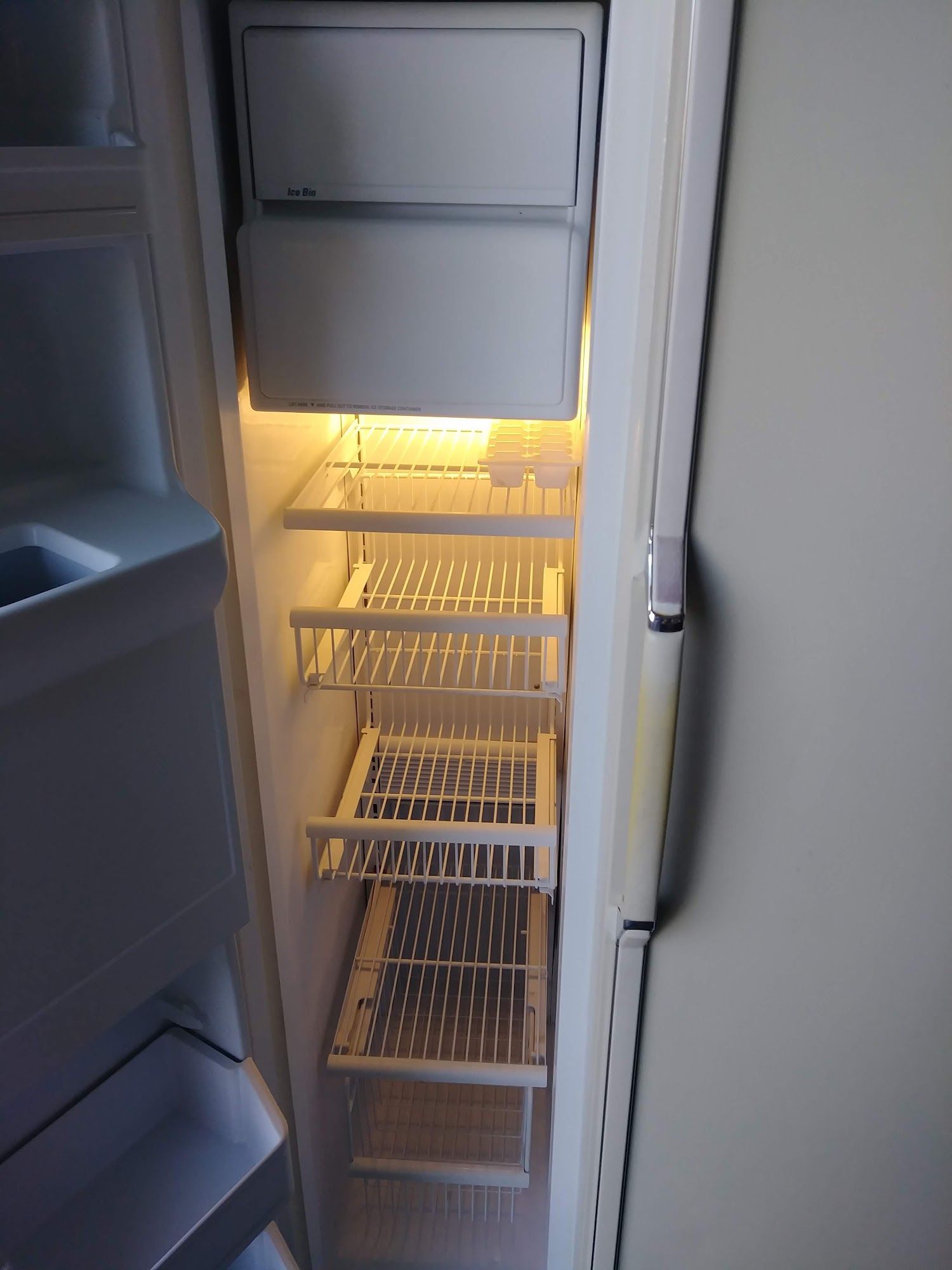 Empty refrigerator interior, showing shelves, light on, and freezer compartment at the top.