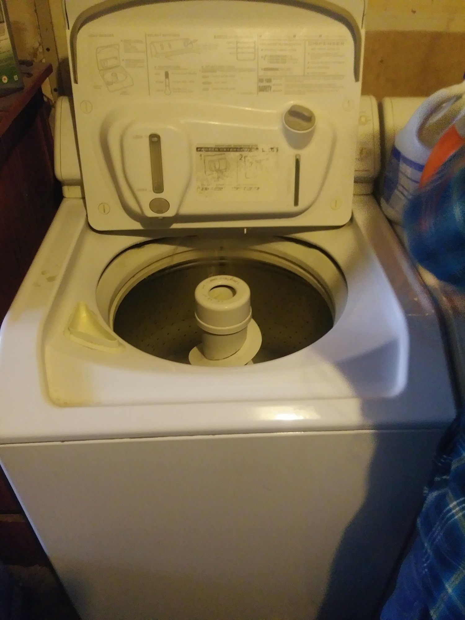 White top-load washing machine with the lid open, showing the interior.