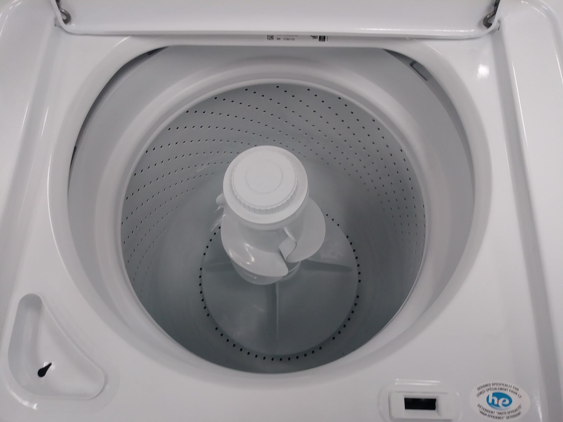 Top-down view of an empty white washing machine interior with an agitator in the center.