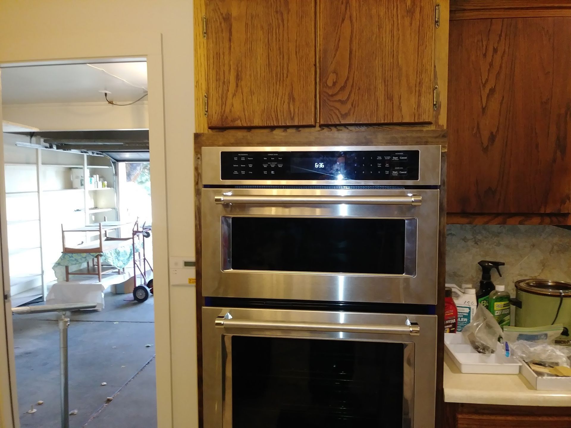 Double oven with stainless steel finish built into wood cabinets, kitchen.