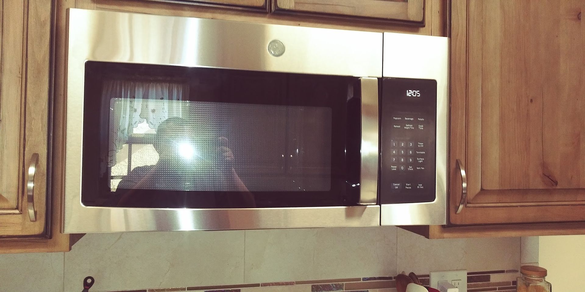 Stainless steel microwave built into brown wooden cabinets.