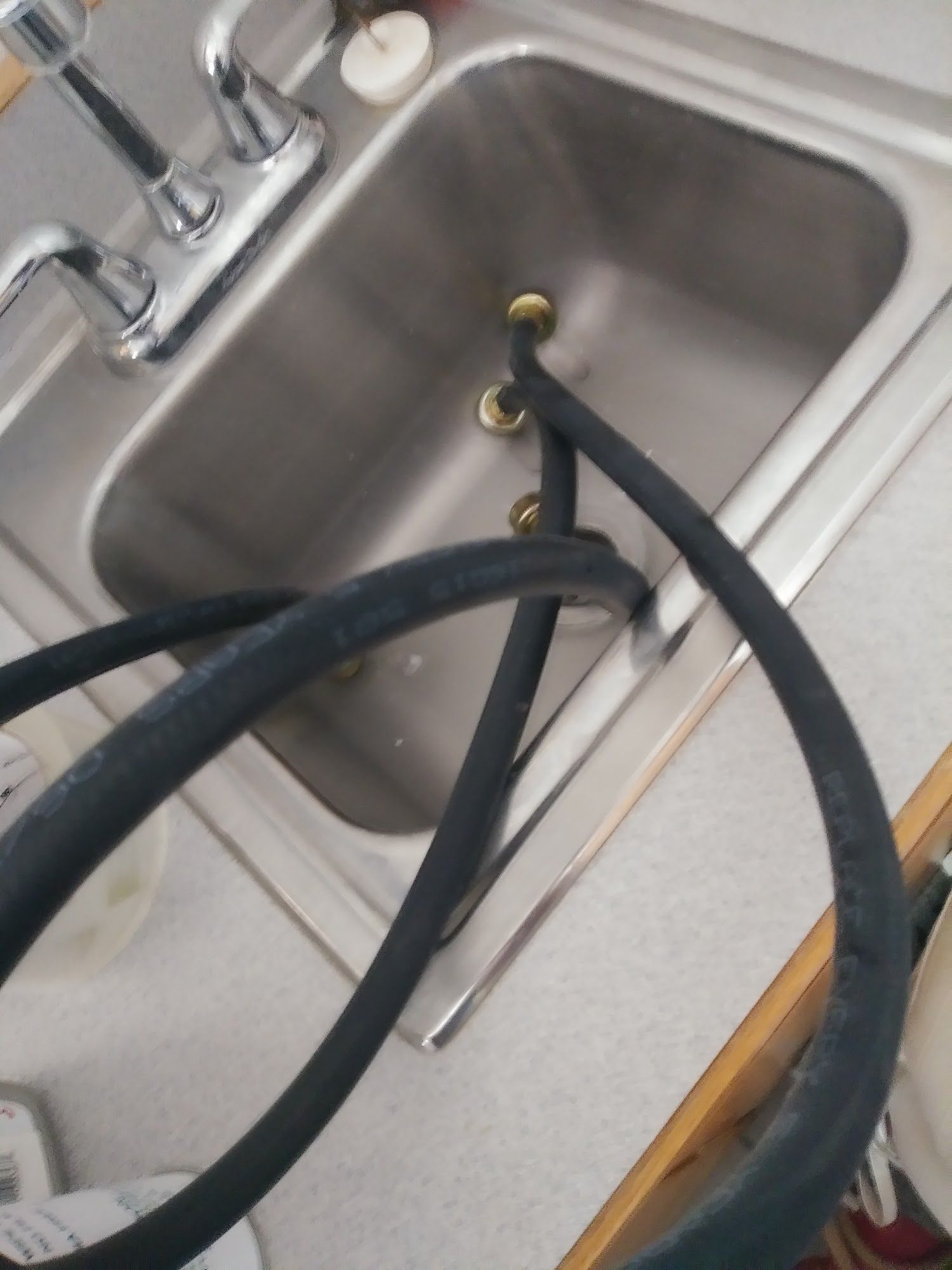 A black hose coiled in a stainless steel sink with a chrome faucet.