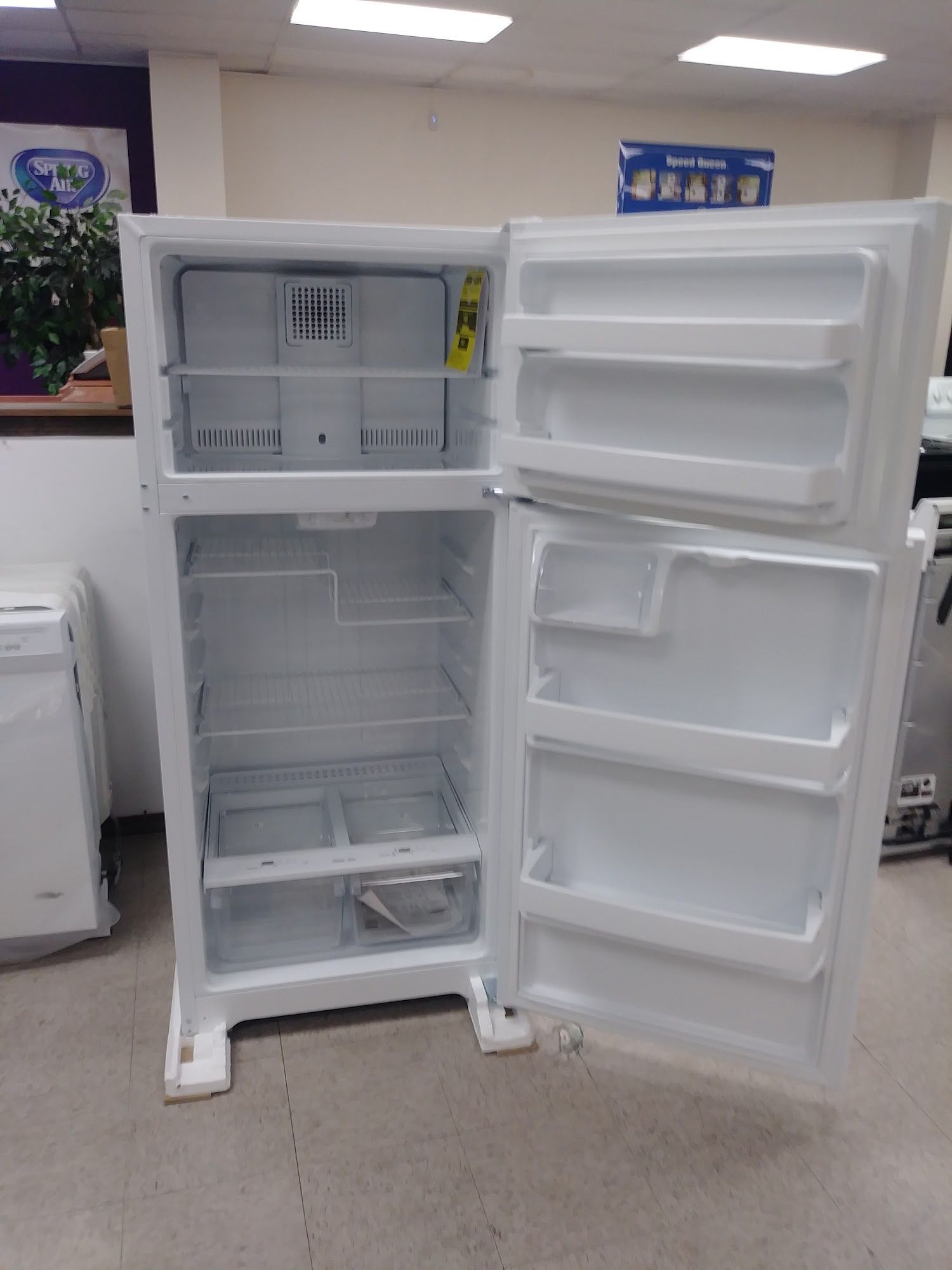 White refrigerator with open doors in a brightly lit store.