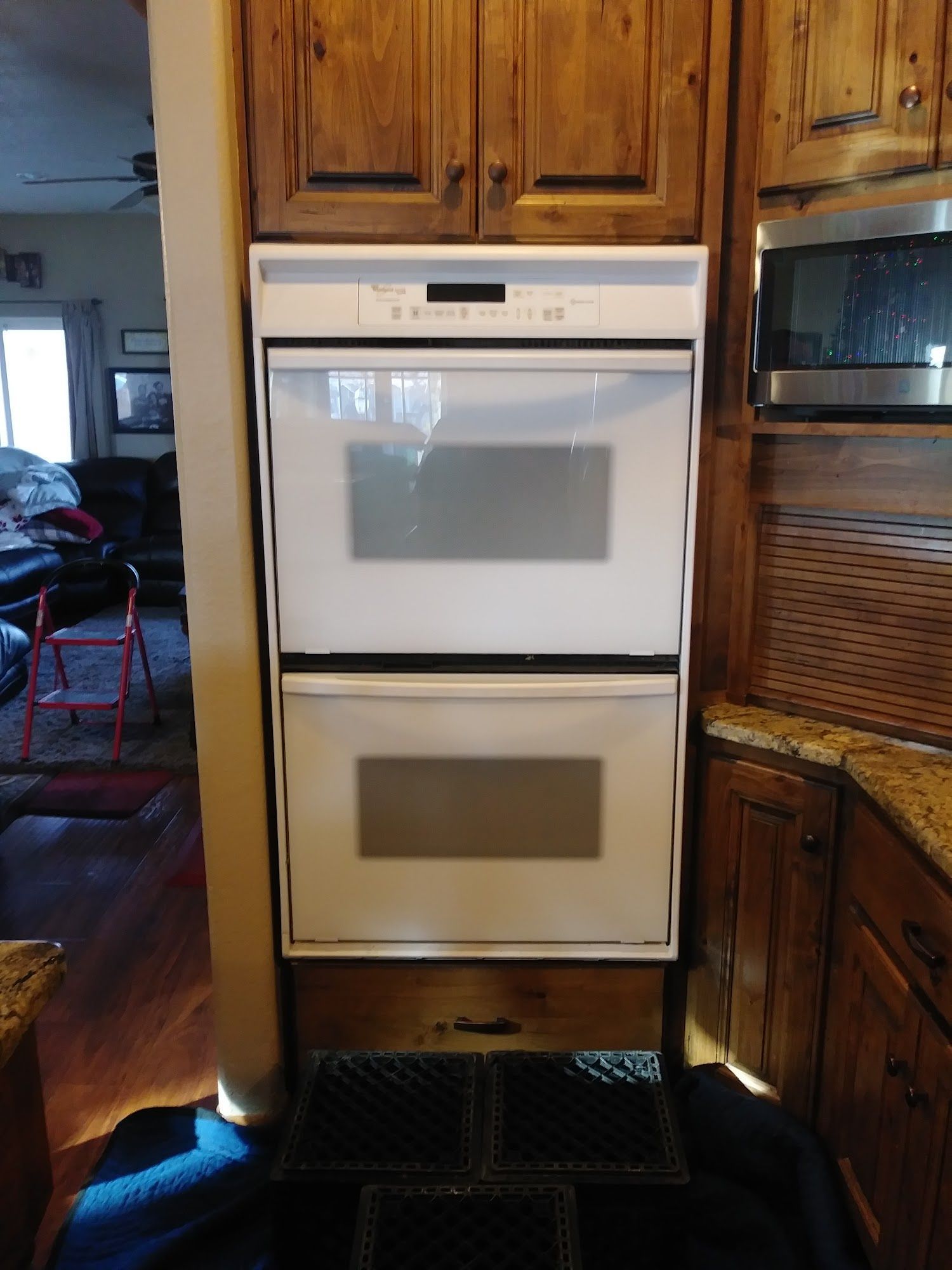 White double oven built into wooden cabinetry. Grids are on the floor.