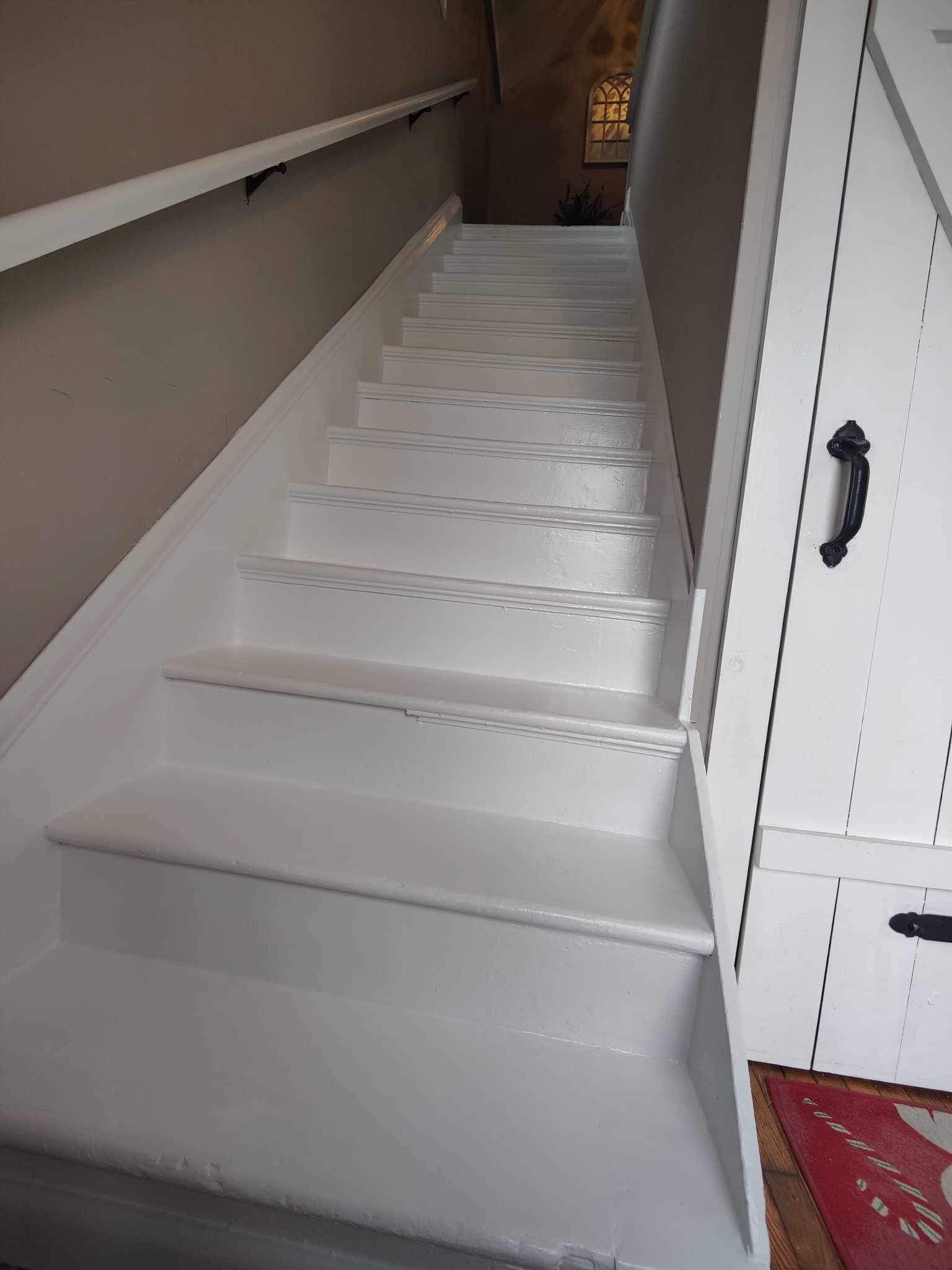 White painted staircase with a handrail, leading upwards.