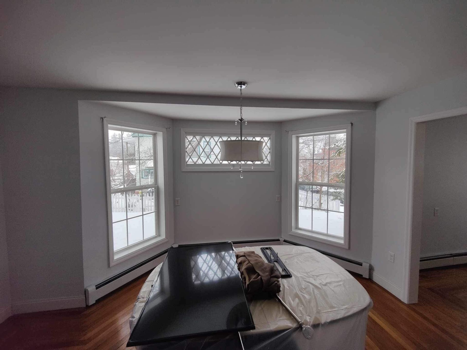 Dining room with bay windows, a large island, and a hanging light fixture.