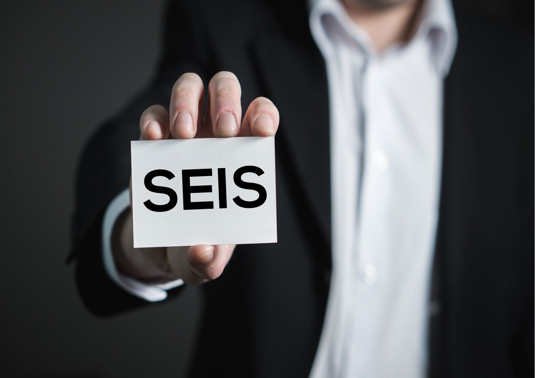 Man holding a card with the letters SEIS on it