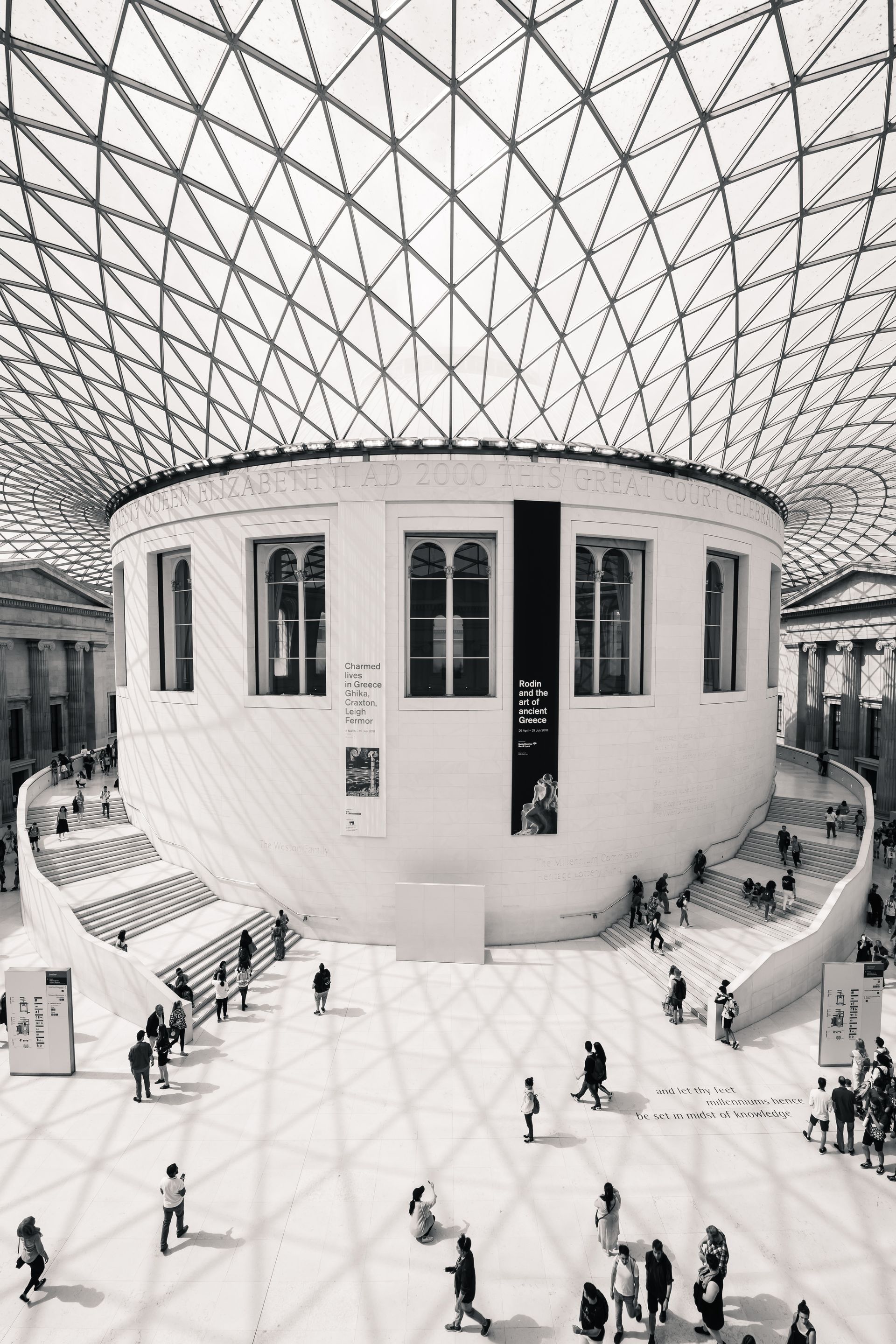 A black and white photo of people walking around the British Museum