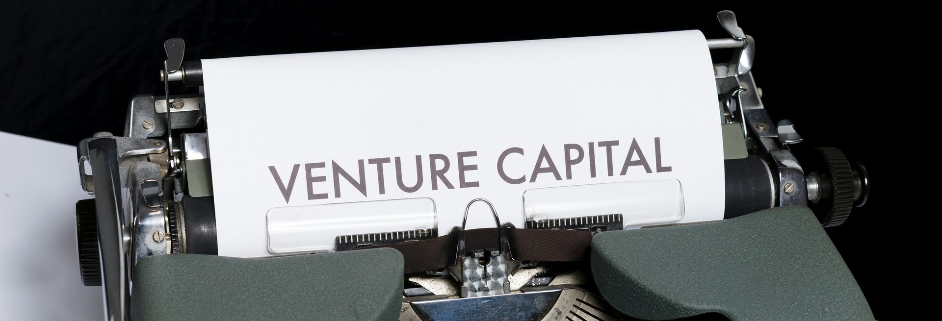 A person is typing the word venture capital on a typewriter