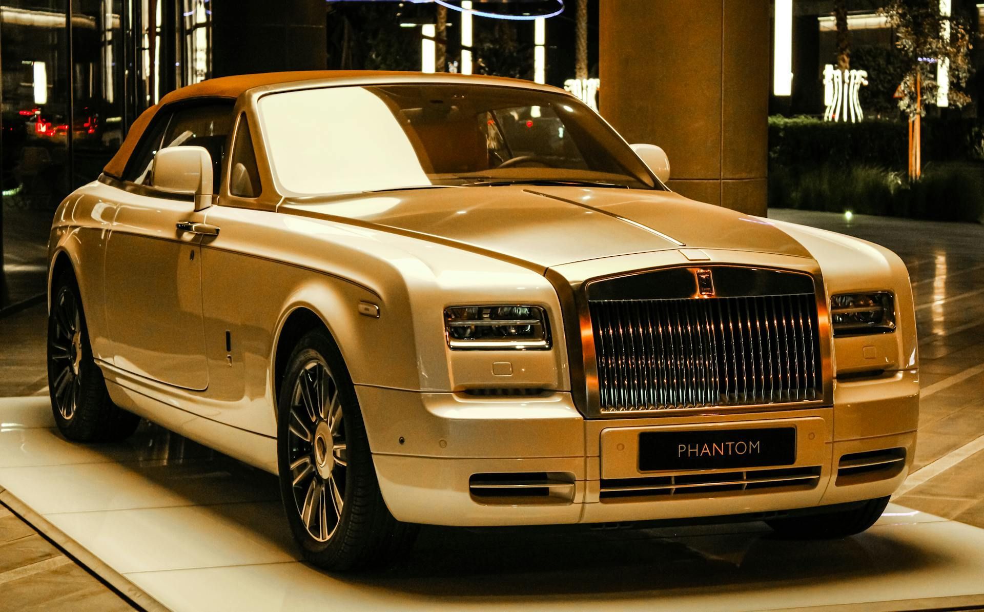 A gold colored rolls royce phantom is on display