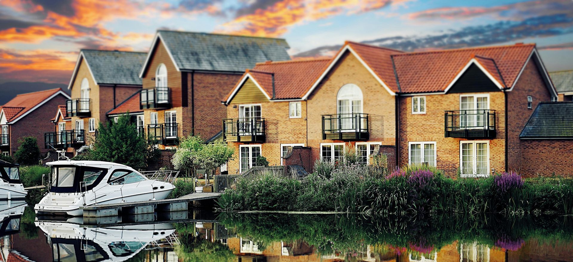 A row of houses next to a body of water with boats docked in front of them.