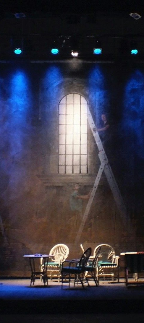 A man is kneeling on a bed next to a tiger puppet on a stage from the play Life of Pi