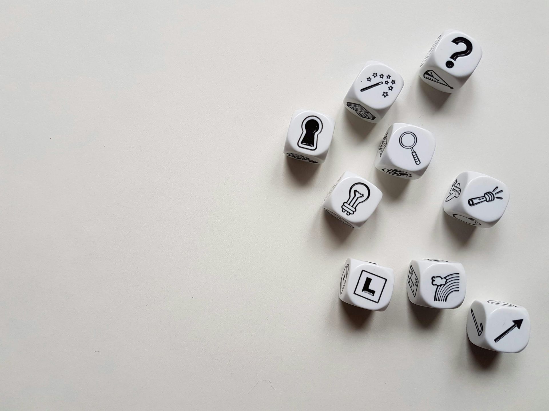 A bunch of dice with icons on them on a white surface.