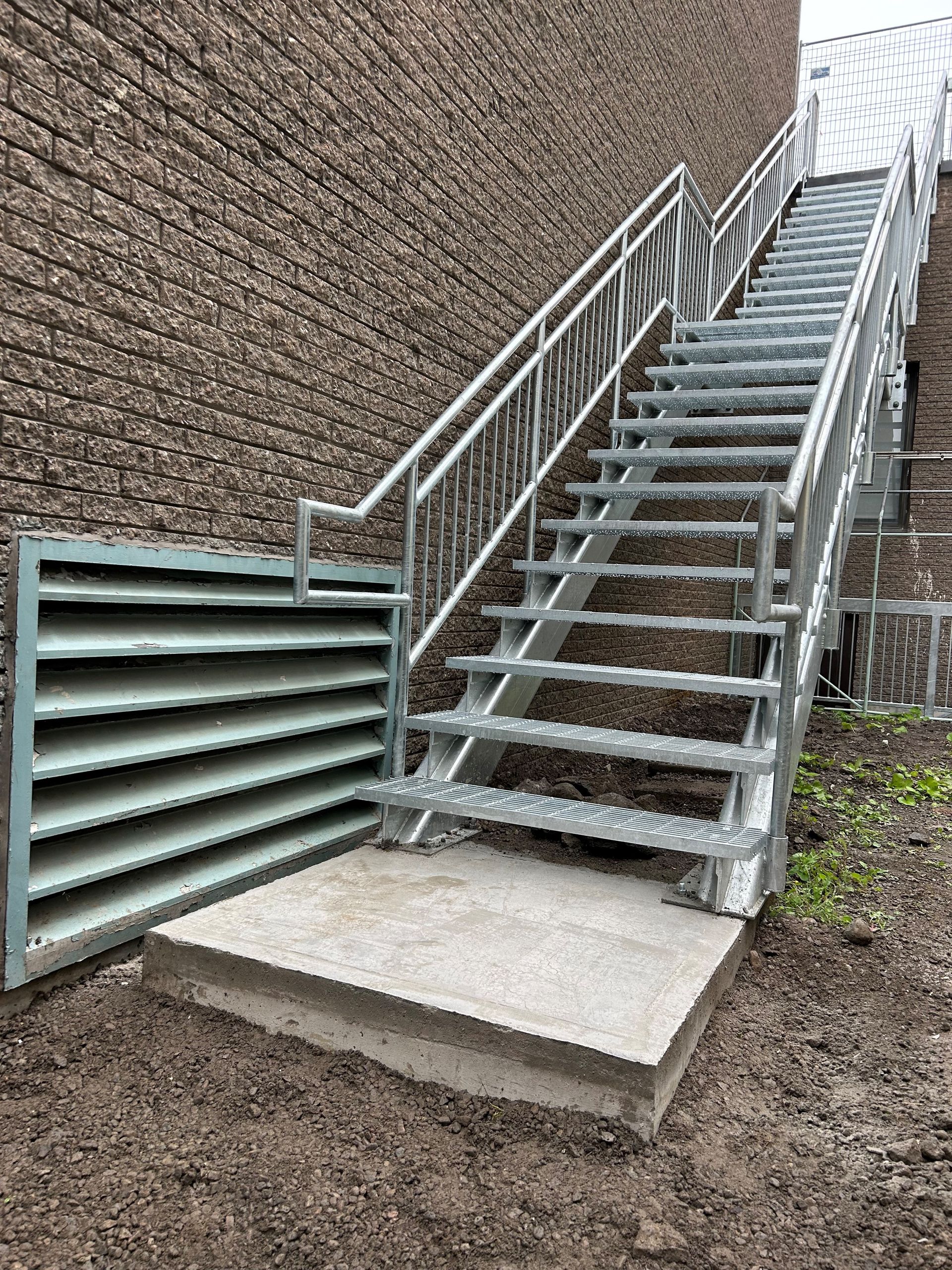 Un escalier métallique menant à un bâtiment en brique.