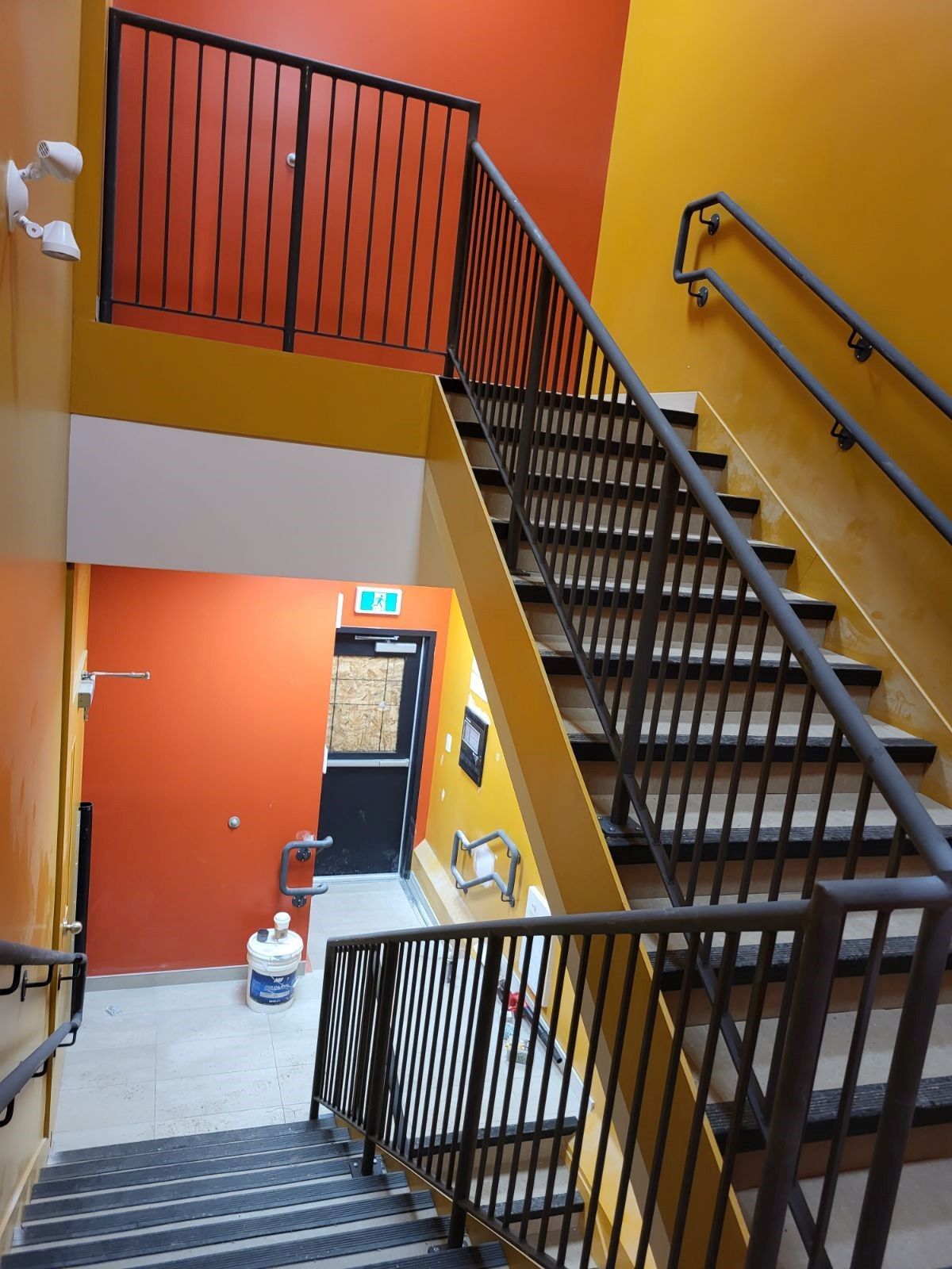 Un escalier avec une rampe en métal et des murs orange