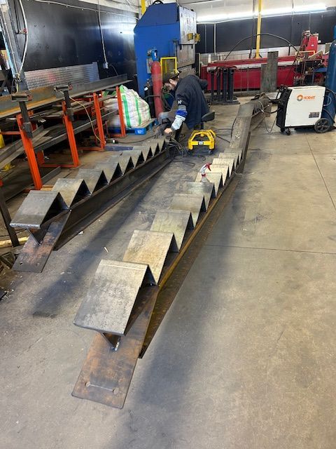 Un homme soude un morceau de métal dans une usine.