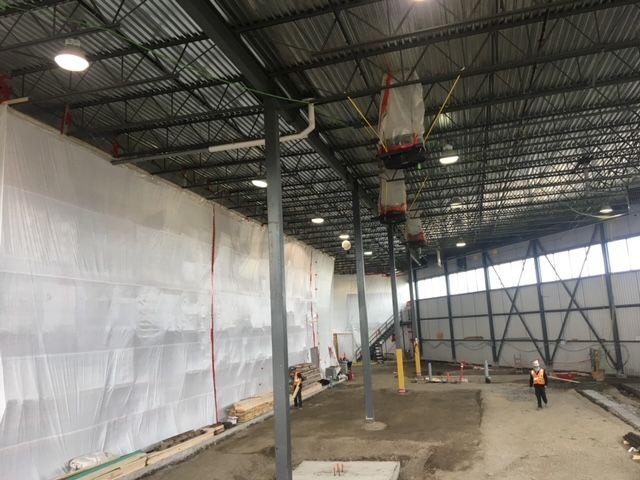Un homme portant un casque de sécurité traverse un grand bâtiment en construction.