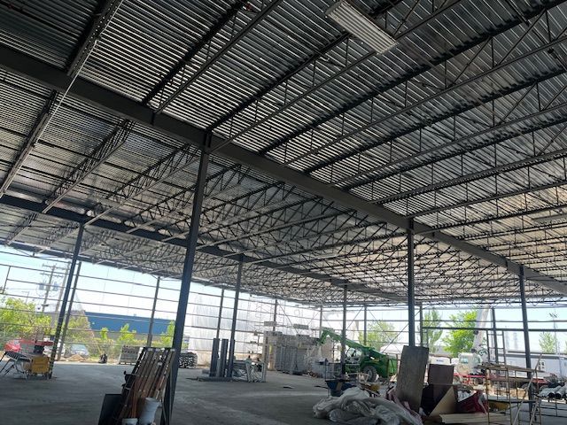 Un grand entrepôt avec une toiture métallique est en cours de construction.