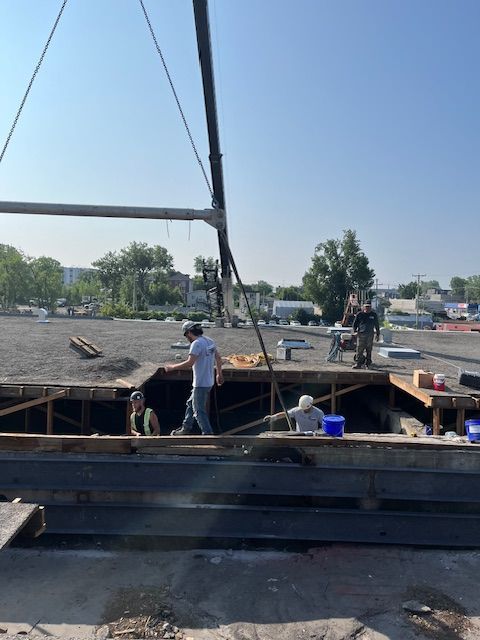 Une grue soulève un gros morceau de métal sur un chantier de construction.