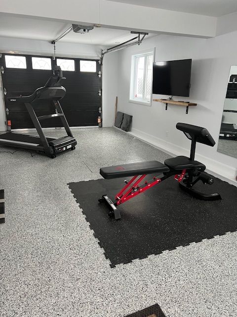 Il y a un tapis roulant et un banc dans le garage.