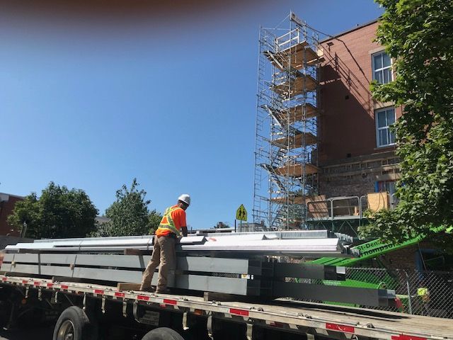 Un ouvrier du bâtiment charge un camion avec un échafaudage dessus.