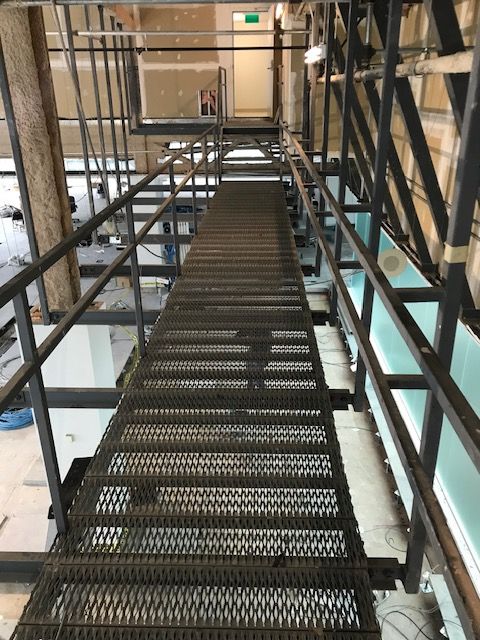 Un escalier métallique avec une rampe montant jusqu'au sommet d'un immeuble