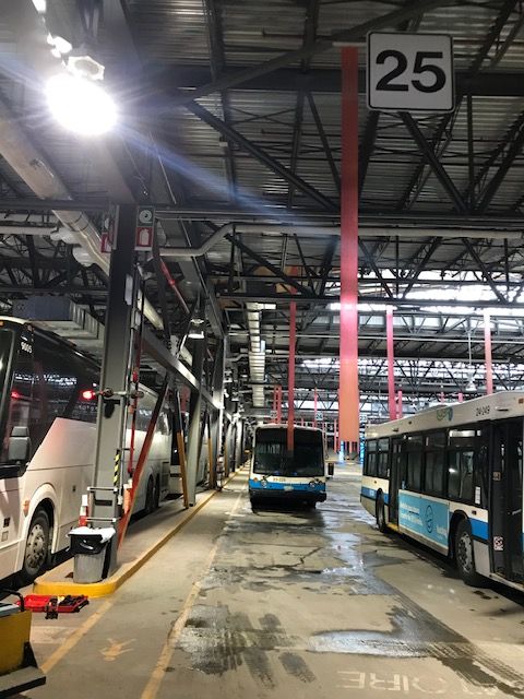 Plusieurs bus sont garés dans un entrepôt avec un panneau indiquant 25