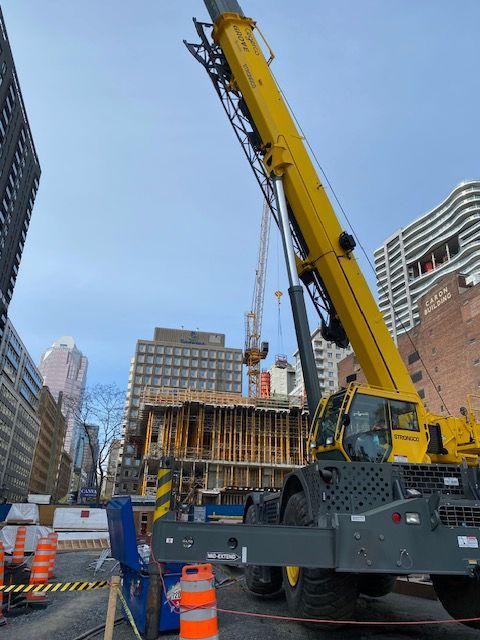 Une grande grue jaune est garée devant un immeuble en construction.