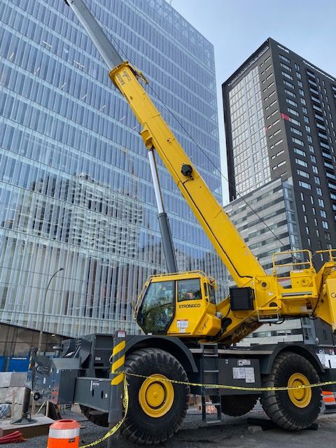 Une grande grue jaune est garée devant un grand bâtiment