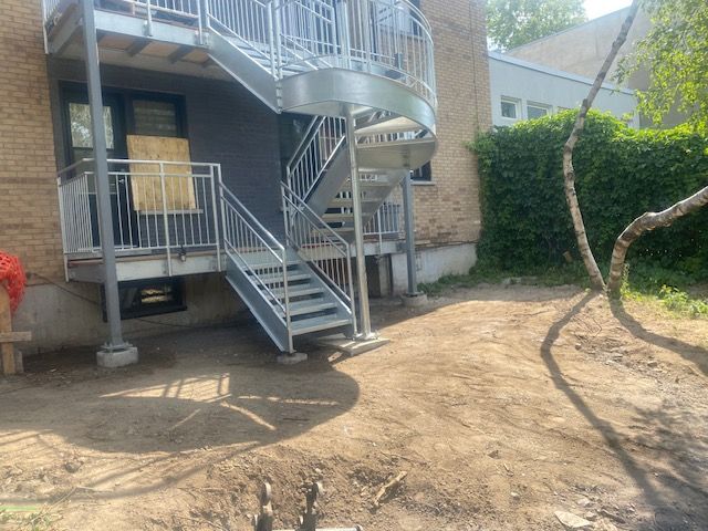 Il y a un escalier en colimaçon dans la cour d’une maison.