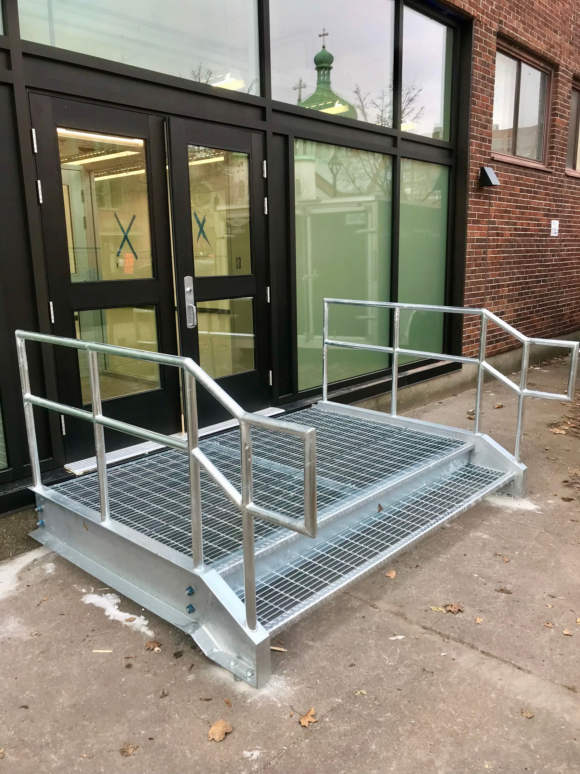 Une rampe métallique avec des escaliers menant à un bâtiment.