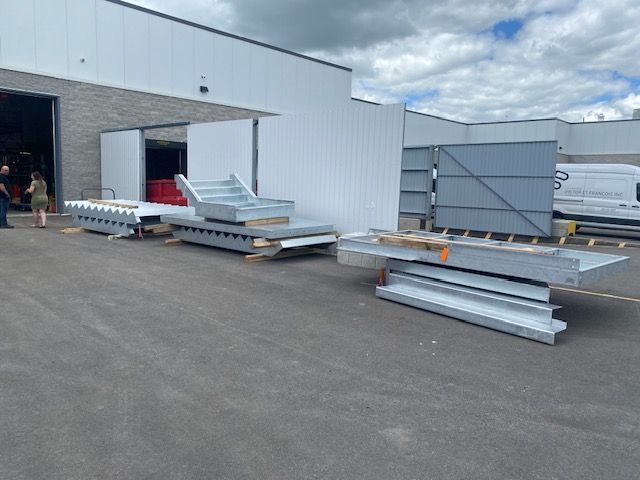 Un tas de pièces métalliques sont posées devant un immeuble.