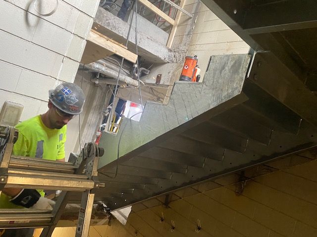 Un homme portant un casque de sécurité se tient debout sur une échelle dans une pièce.