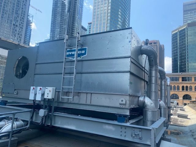 Un grand système de refroidissement se trouve au sommet d’un immeuble dans une ville.