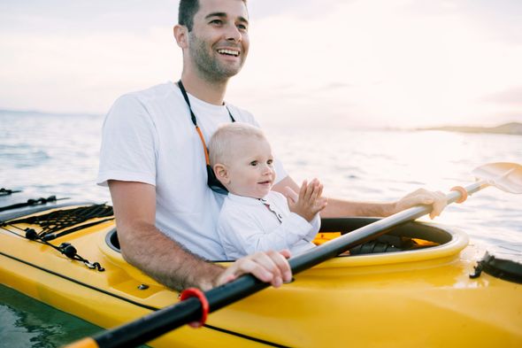 A man is holding a baby in a kayak.