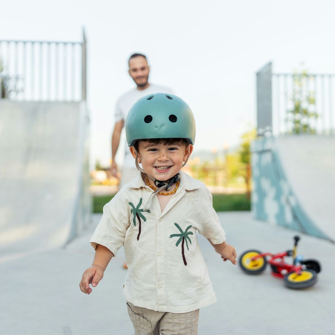 A little boy wearing a helmet and a shirt with palm trees on it