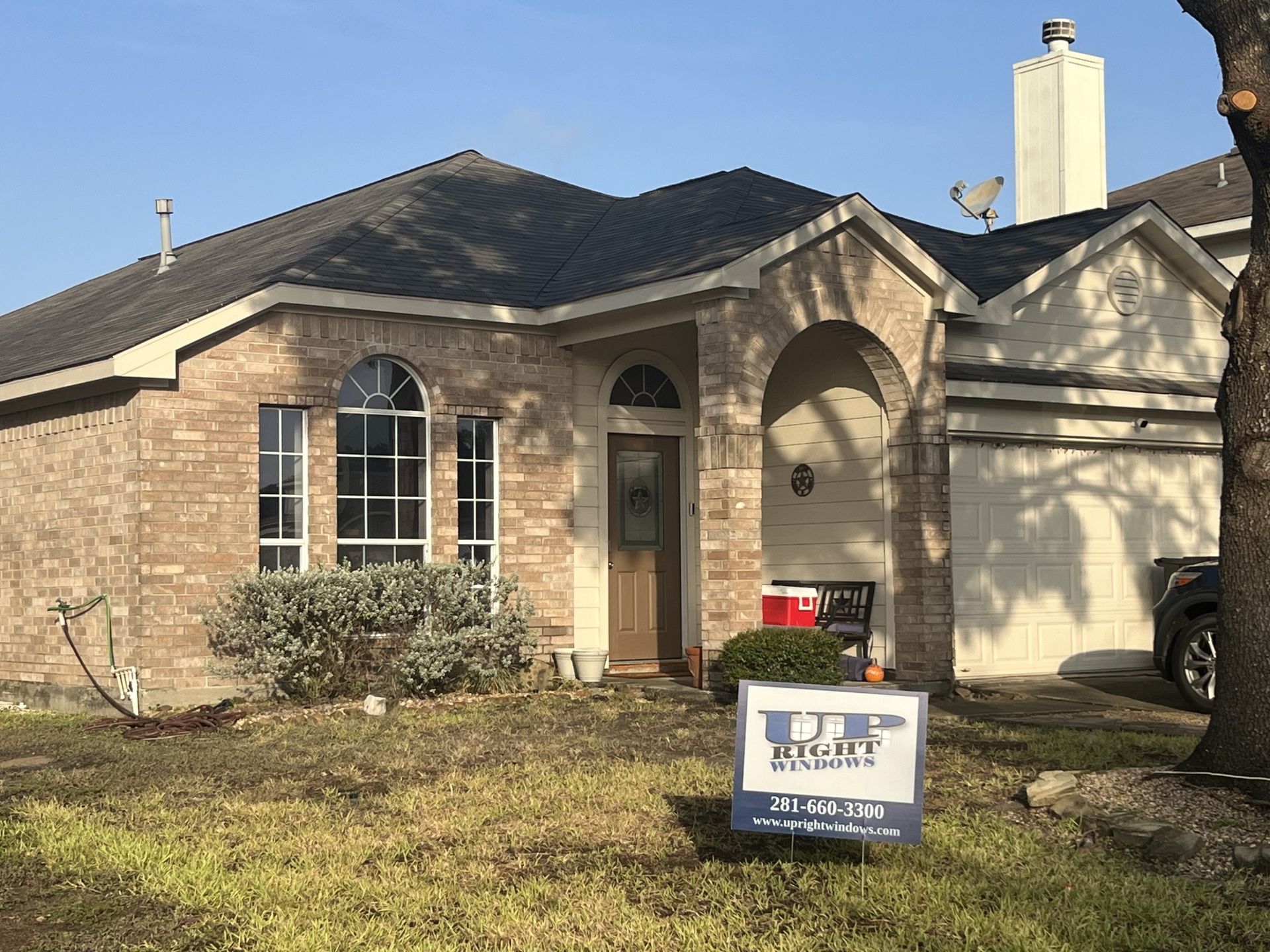 Single-story brick house with a front garage and a real estate sign on the front lawn.