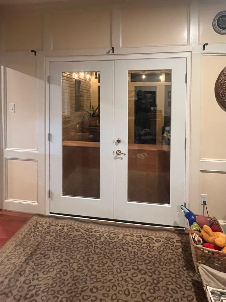 A pair of white, glass-paneled double doors centered in a paneled wall above a leopard-print rug.