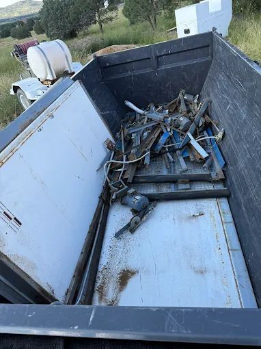Dump truck bed filled with scrap metal. Gray and blue metal pieces inside the truck bed.